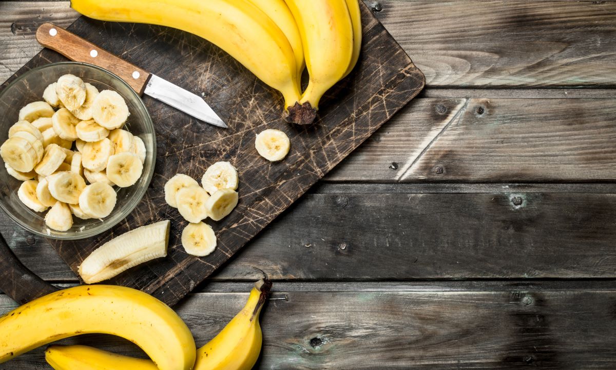 Fresh bananas being sliced on a cutting board.