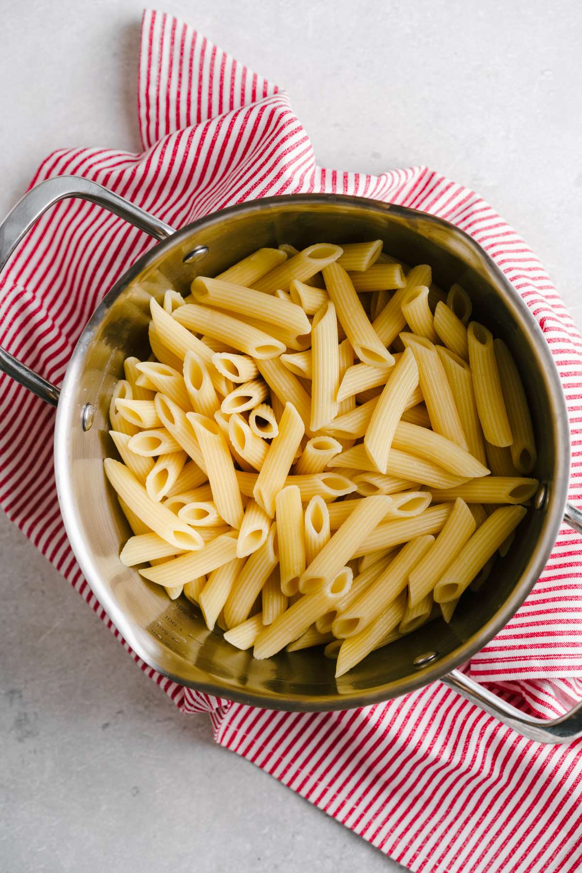 Penne pasta strained in a strainer.