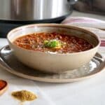 A bowl of chili topped with avocado.