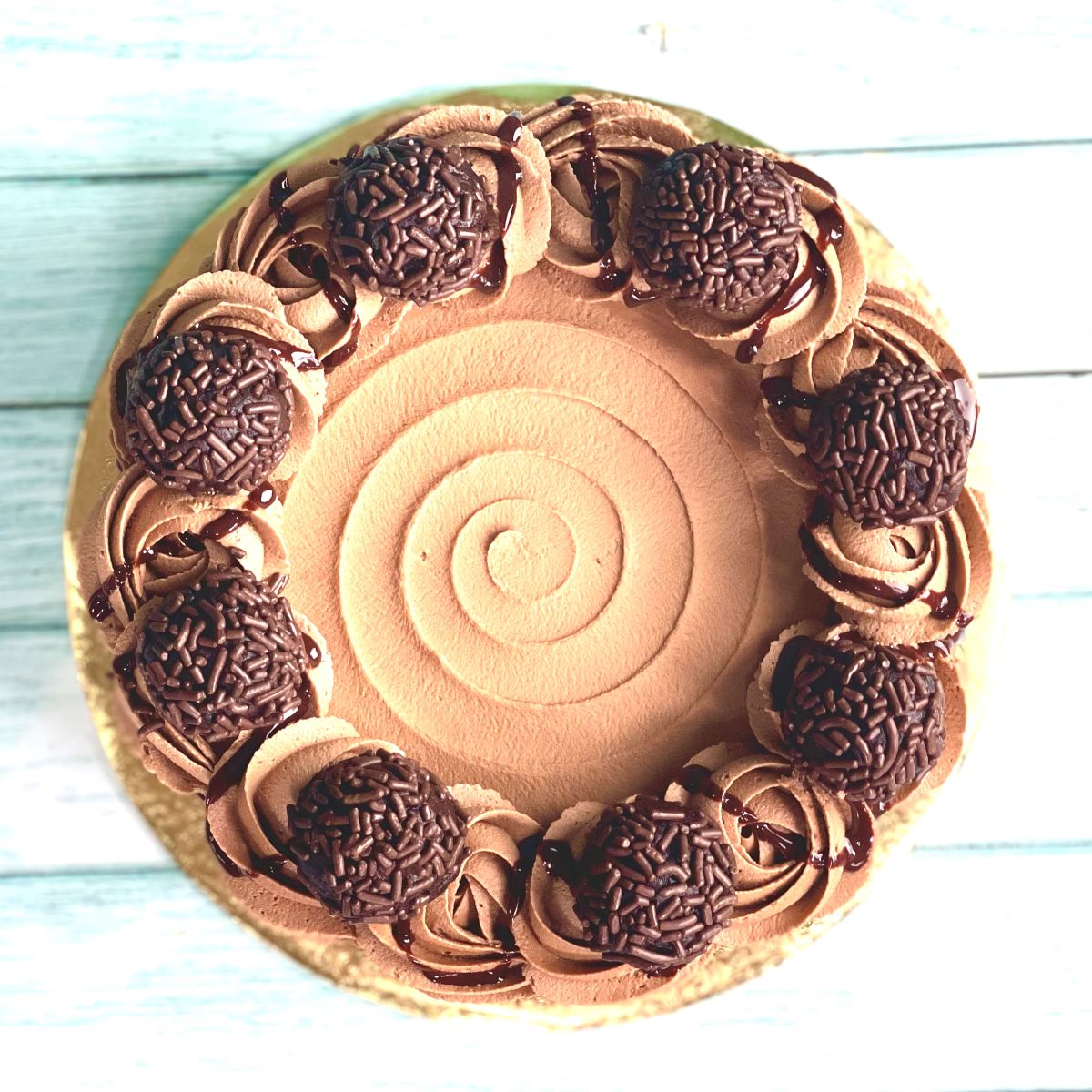An overhead shot of a chocolate cake decorated with chocolate cake truffles.