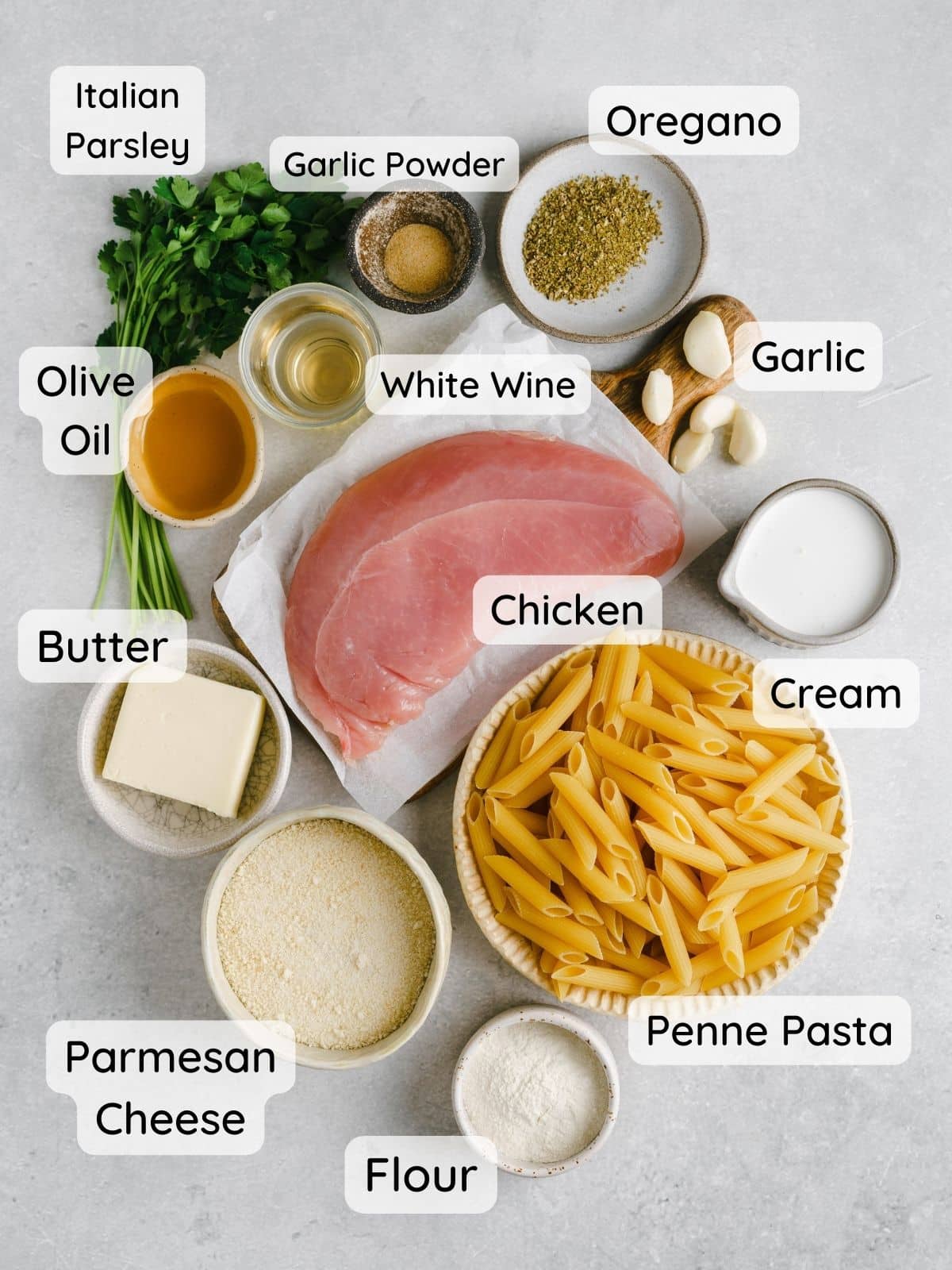 A shot of all the ingredients in this recipe with the following text: chicken, penne pasta, butter, olive oil, cream, white wine, italian parsley, oregano, garlic powder, chicken, garlic, flour."